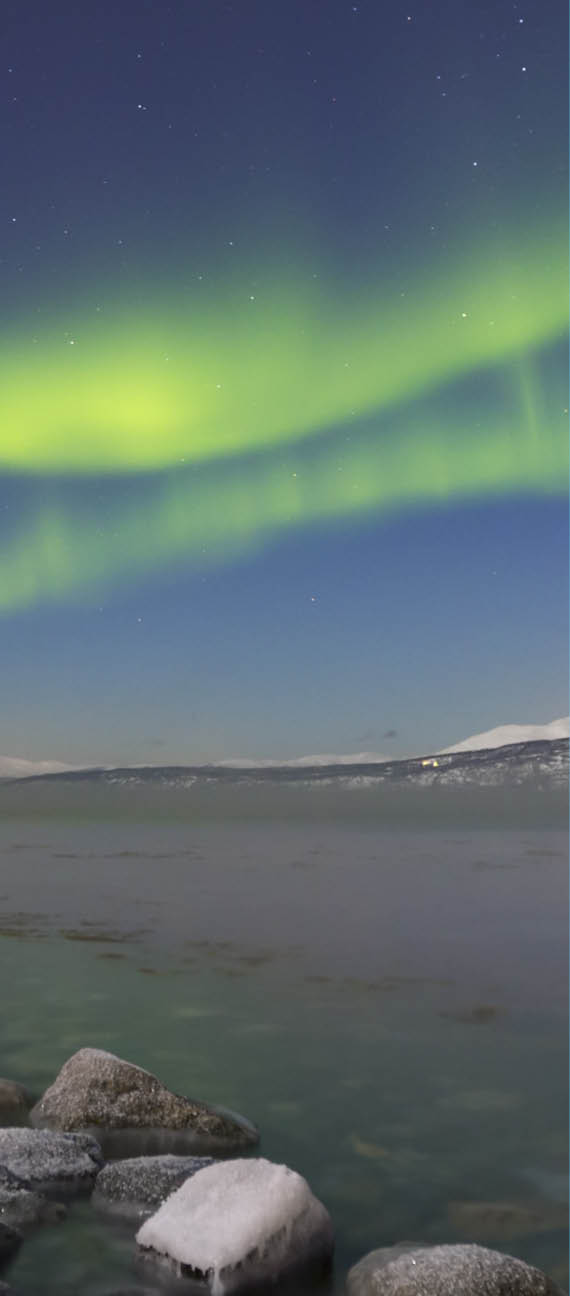The aurora borealis over a moonlit fjord in northern Norway in winter 