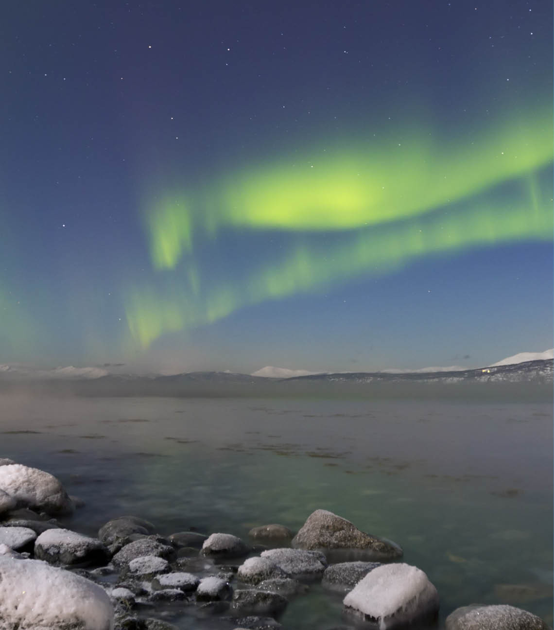 The aurora borealis over a moonlit fjord in northern Norway in winter 