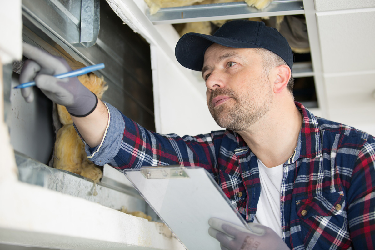 Photo of a man inspecting the insulation installation quality in a wall cavity. 