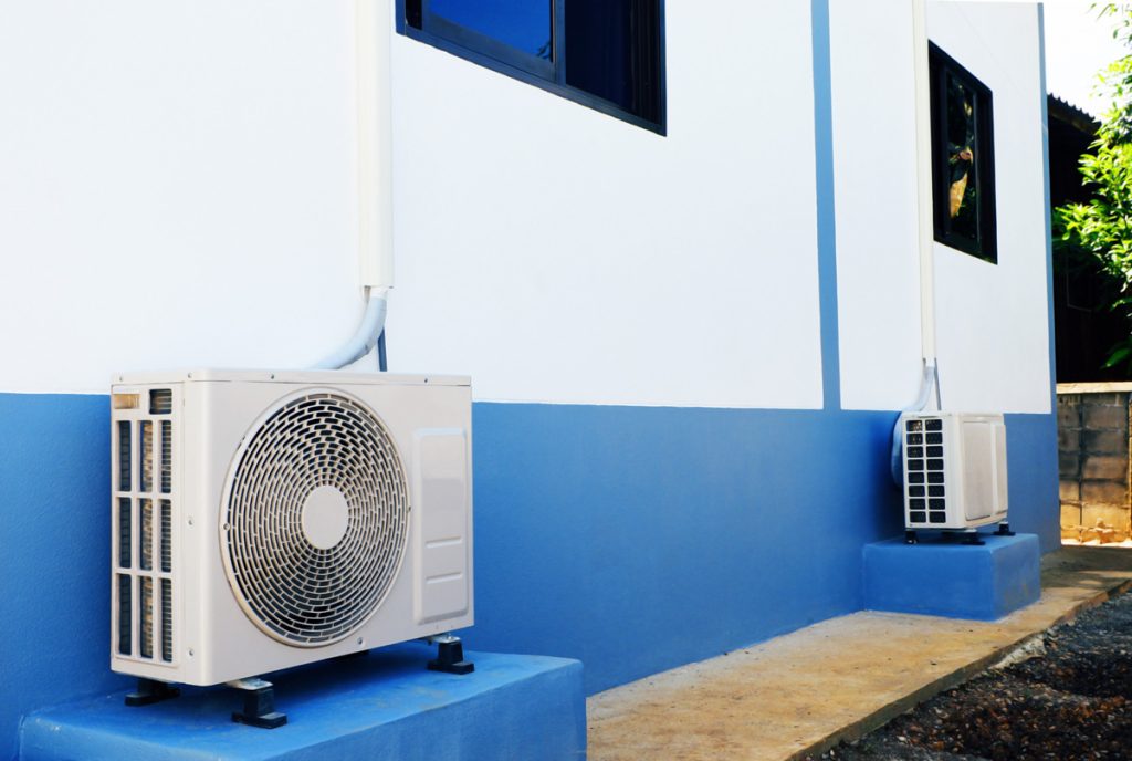 Air source heat pumps behind a multi-unit dwelling.