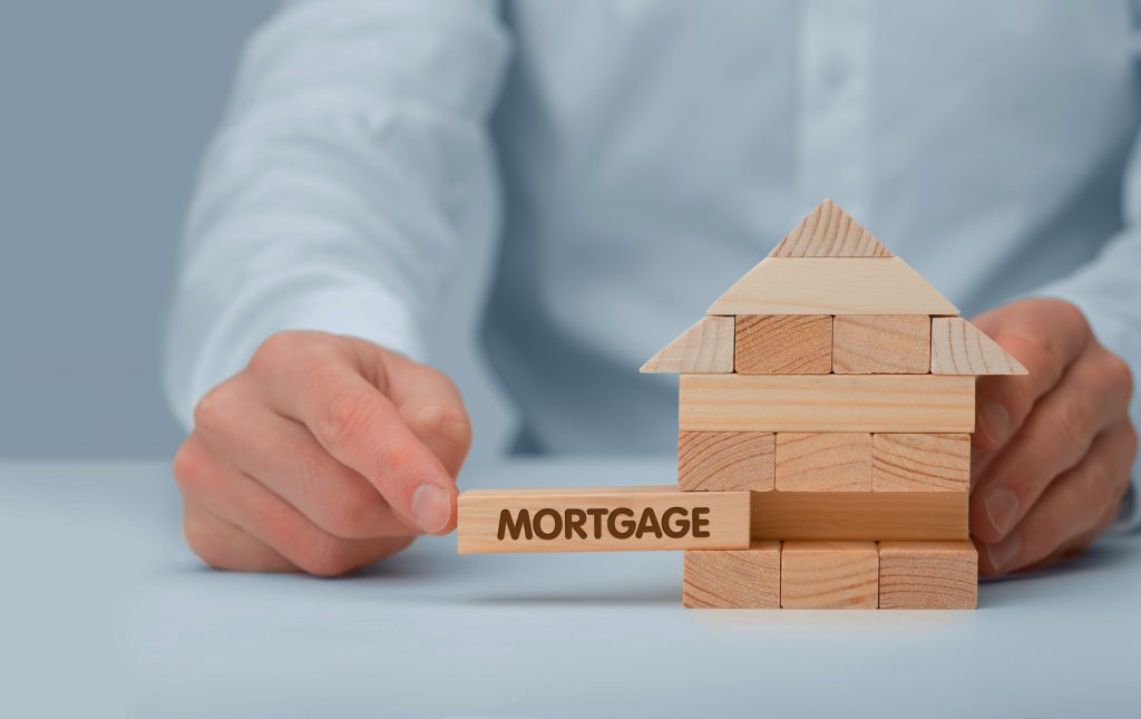 Conceptual photo showing a house of building blocks with the mortgage block being shown as a critical piece of the home building and buying process.